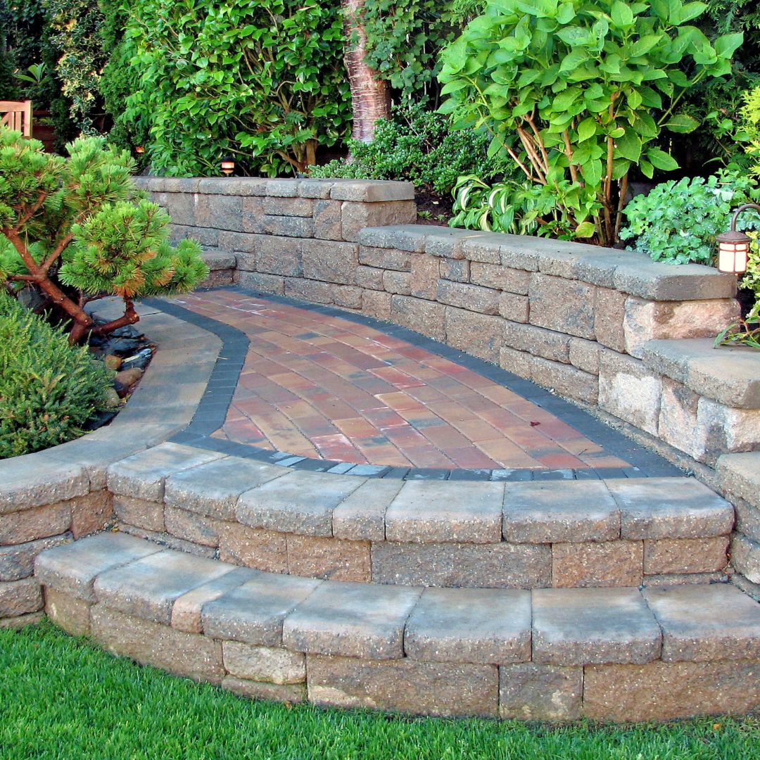 Curved stone patio with brick pathway and surrounding landscaped garden