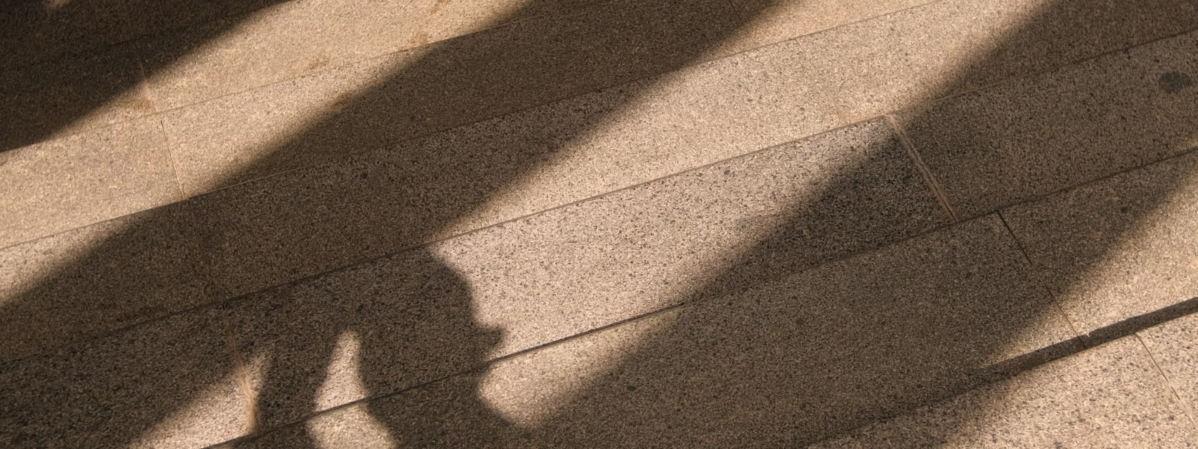 Shadows cast on textured tile or stone floor with diagonal light lines
